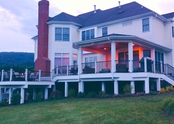 Blue-hour view of a custom rear deck and covered porch.