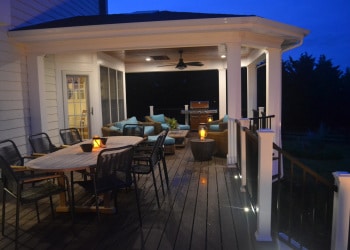 Twilight dining area and covered deck with landscape lighting.