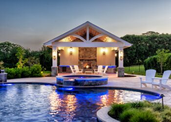 Illuminated pavilion and spa beside the custom pool at twilight