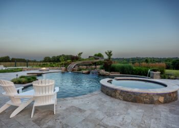 Spa and freeform pool framed by the landscaped waterslide and fire feature