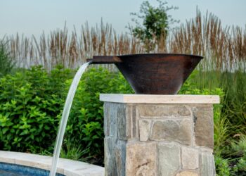 Copper water bowl feature spilling into the illuminated pool
