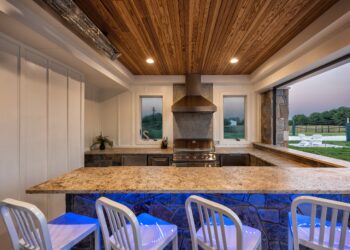 Outdoor kitchen with stone bar and a view toward the pool terrace