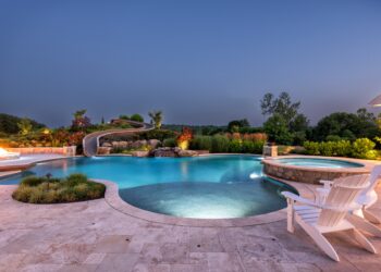 Blue-hour pool panorama with spa waterslide and illuminated pavilion