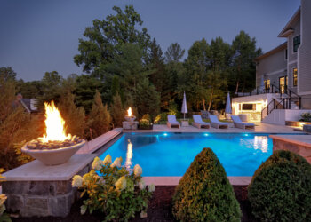 Blue-hour pool view with spa fire bowls and refined limestone terrace