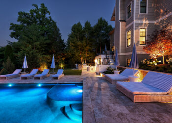 Symmetrical twilight view across the pool terrace and lounge seating