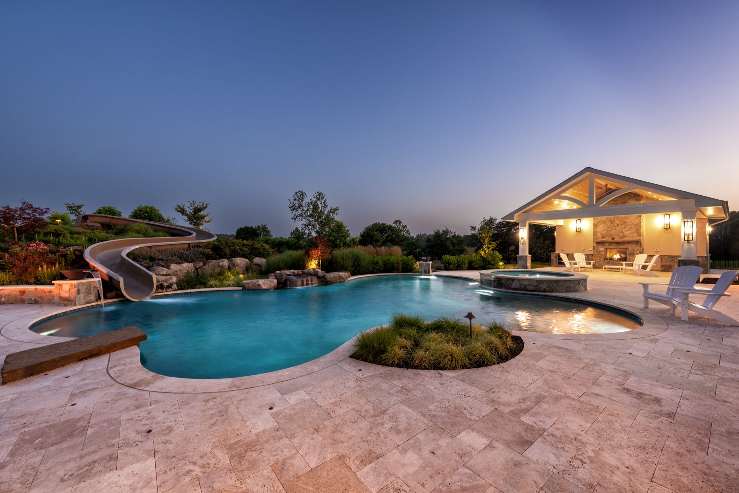Twilight view of the freeform pool waterslide spa and pavilion at Sliding into Relaxation in Purcellville