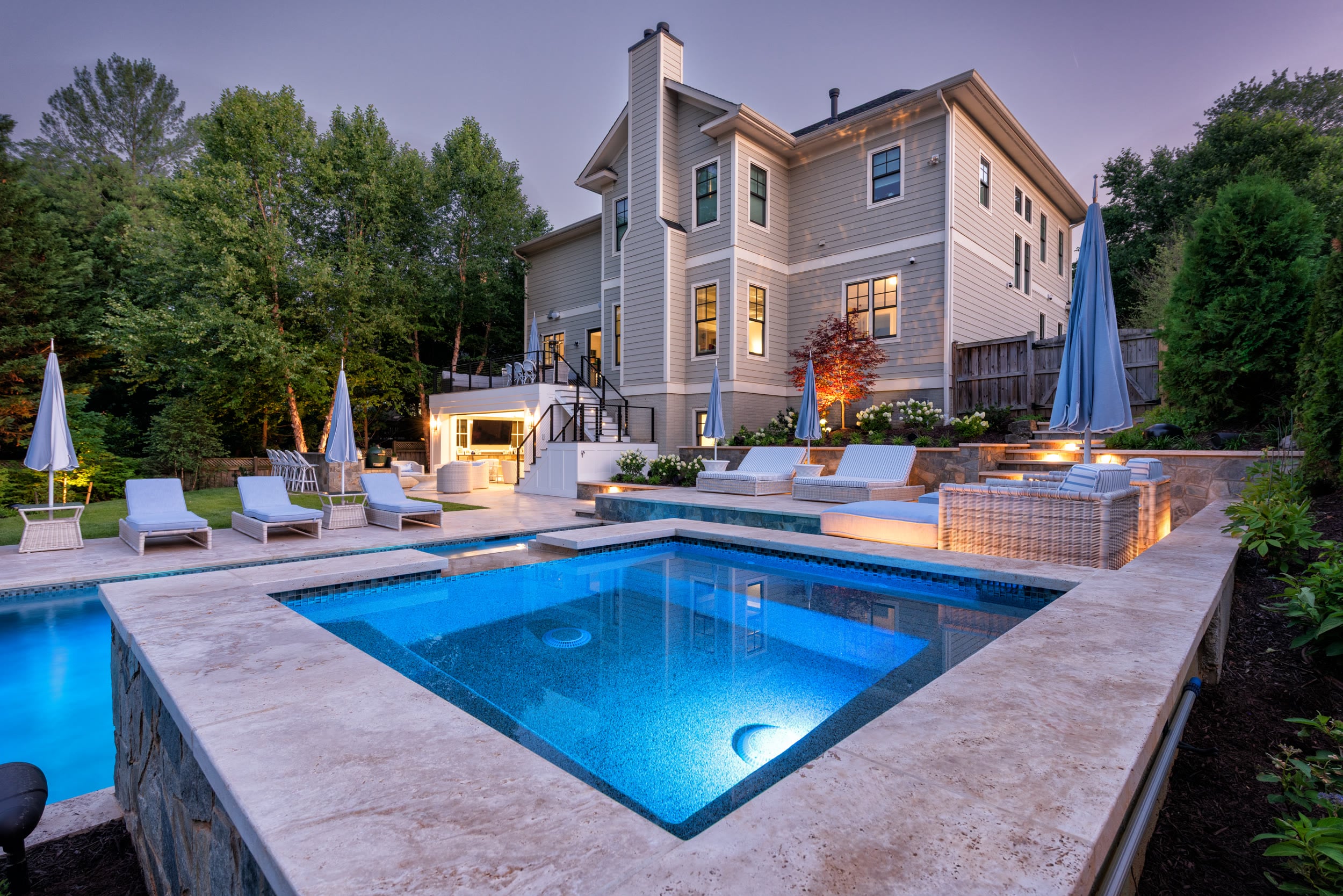 Twilight overview of the terraced pool spa fire bowls and multi-level outdoor living space